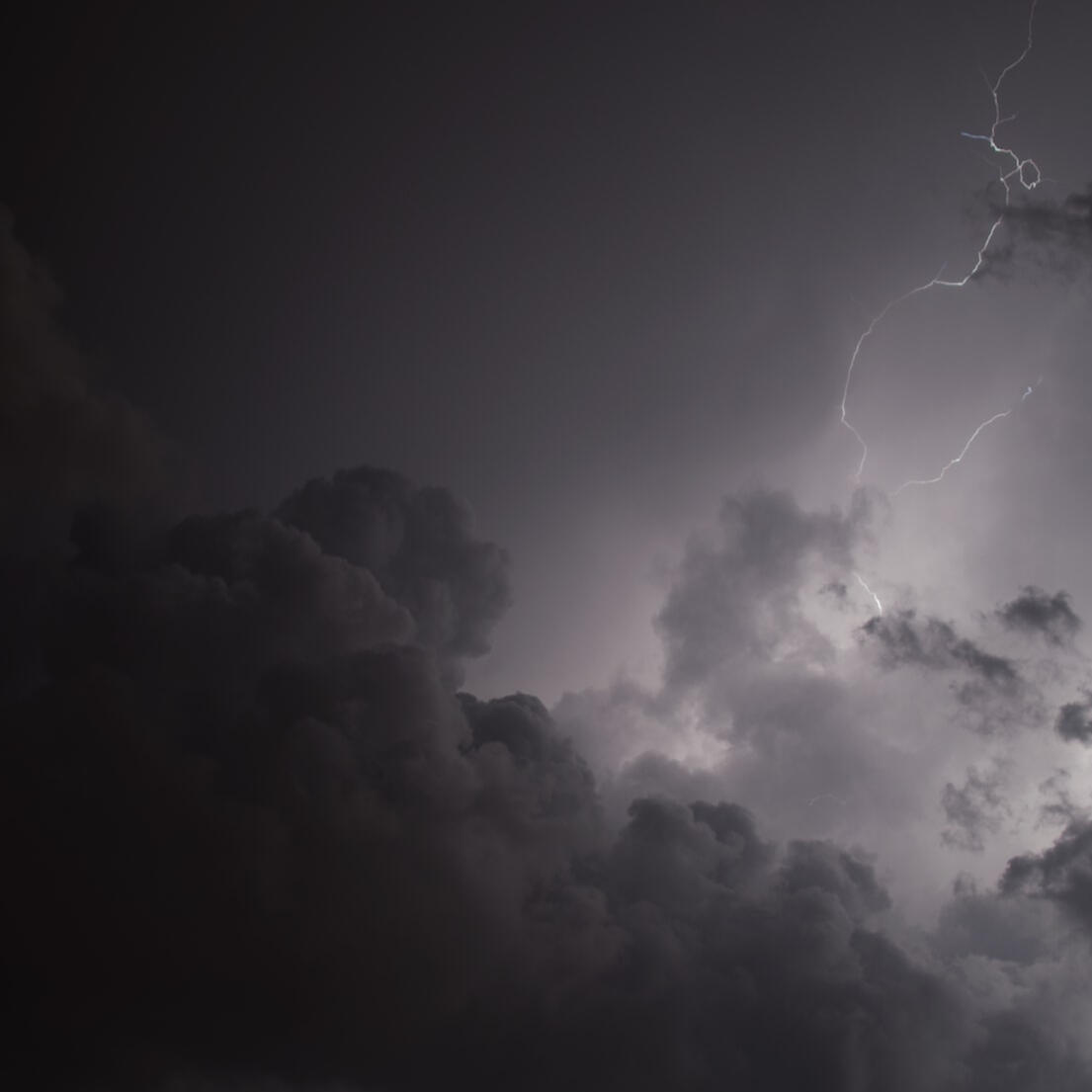 A monochromatic grey sky. There is a dark cloud in the bottom left corner and a bolt of lightning along the right edge.