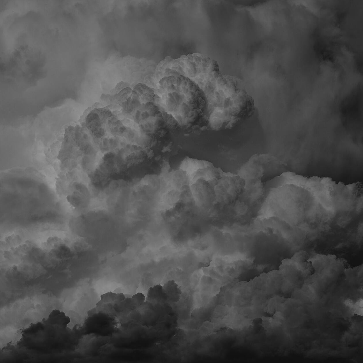 A large, monochromatic grey storm cloud. It gets lighter at the top and darker at the bottom.